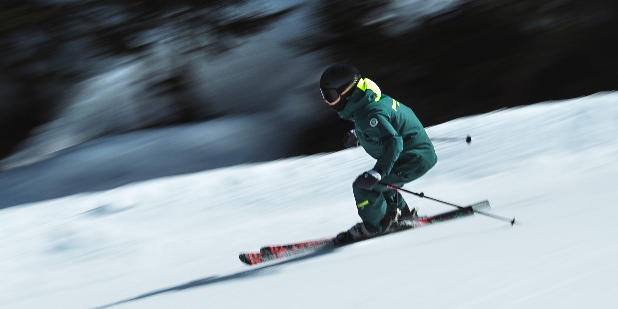 A Performance Verbier instructor carving at speed, snow spraying behind